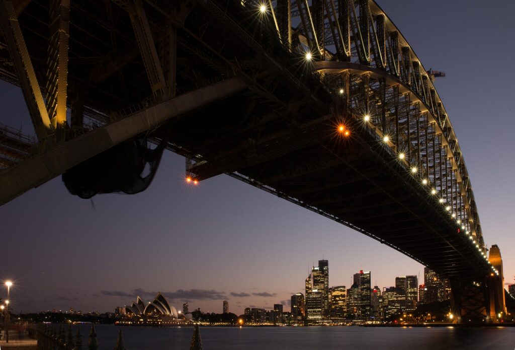 A split image contrasting the iconic landmarks of Sydney, Australia, and Auckland, New Zealand.